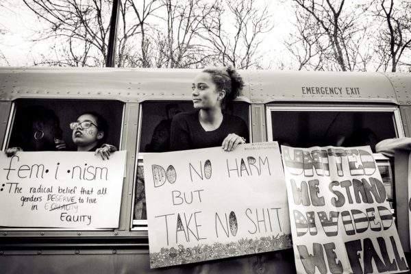 Teenage girl in school bus holding protest sign